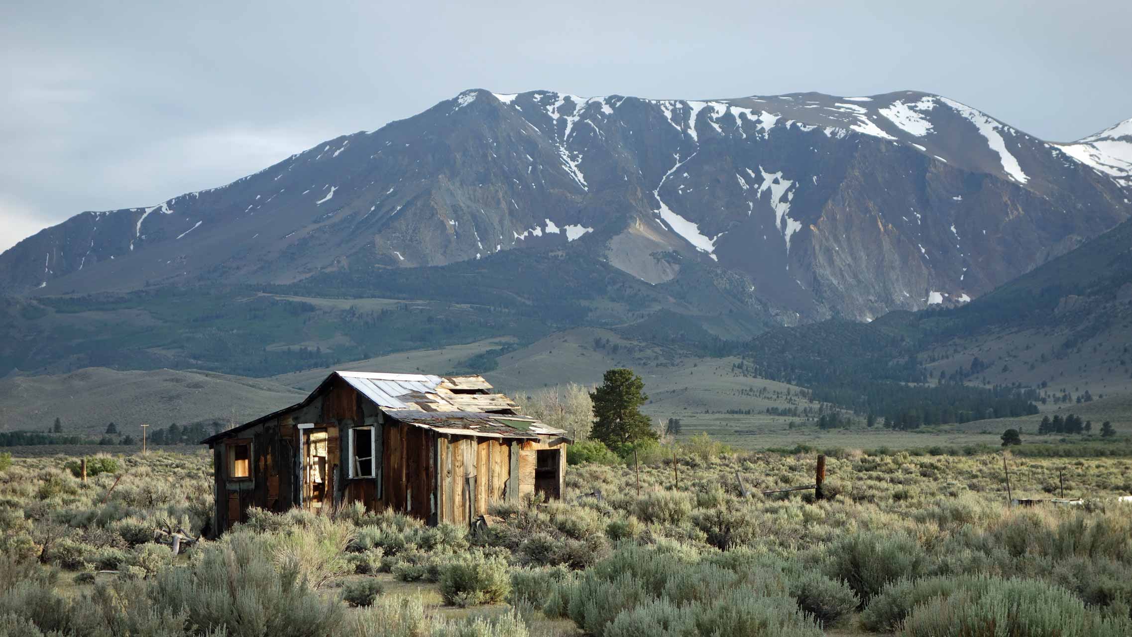 Einsame verfallene Hütte mit Berg-Panorama